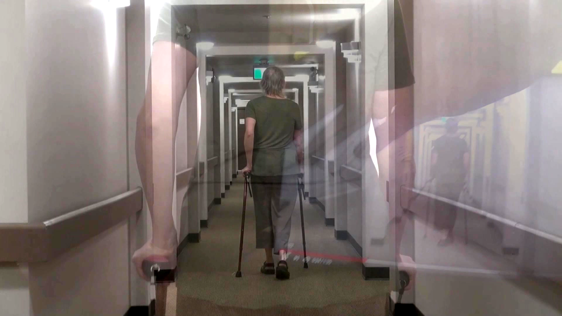A person walking away in a narrow hallway using walking sticks. The person wears a dark green outfit. The image has a multiple exposure effect.